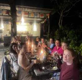 a group of friends and families enjoying dinner in a night setting with lights in the background